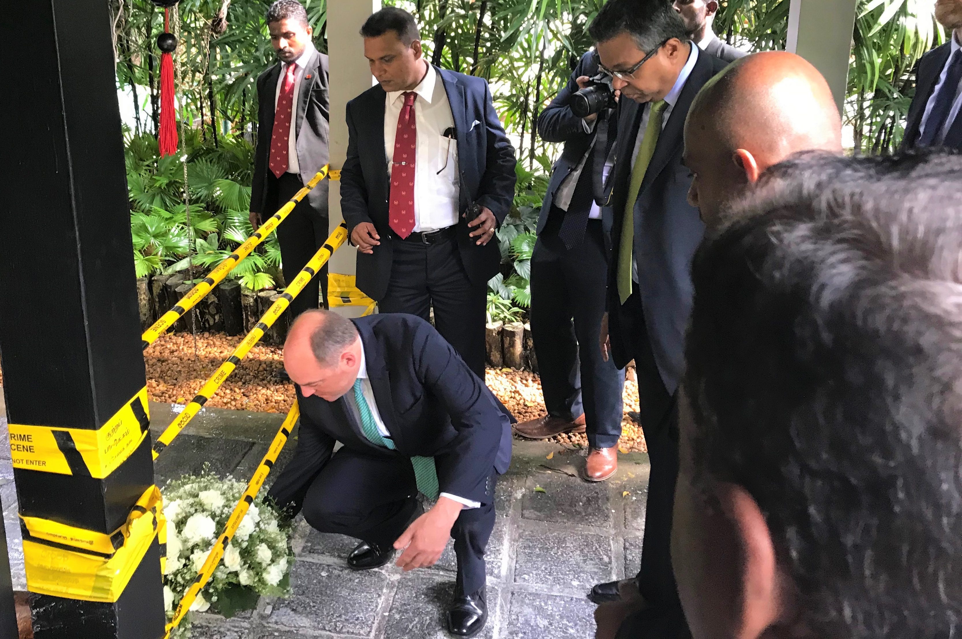 Security Minister, Ben Wallace, lays a wreath on the ground with several people watching.